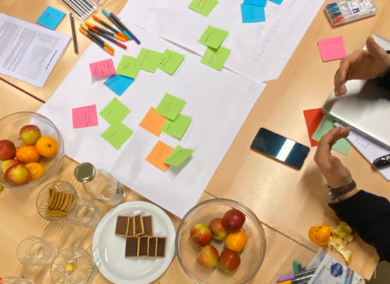 Group of people gathered around a table exchanging colorful sticky notes